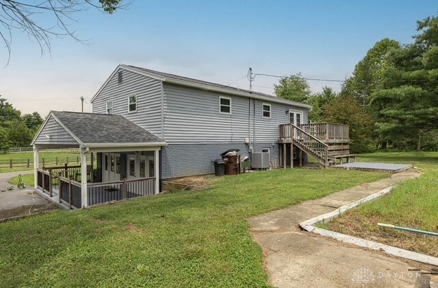 7143 S State Route 123, Blanchester, OH 45107 - rear view of property with a deck, a lawn, stairs, and brick siding