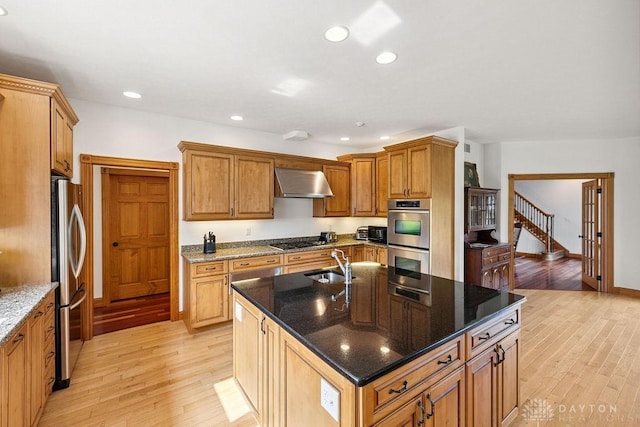 7373 Crowl Rd, Degraff, OH 43318 - kitchen featuring appliances with stainless steel finishes, wall chimney exhaust hood, light wood-style floors, a center island with sink, and recessed lighting