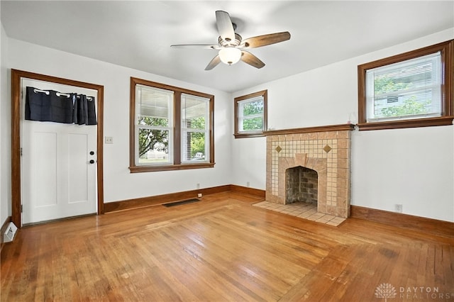 7336 Maple Ave, Cincinnati, OH 45231 - unfurnished living room featuring hardwood / wood-style flooring, a tiled fireplace, and a ceiling fan