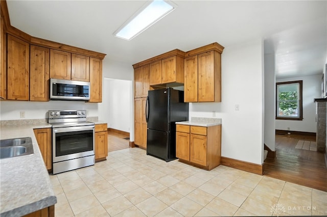 7336 Maple Ave, Cincinnati, OH 45231 - kitchen with stainless steel appliances, brown cabinets, light countertops, and light tile patterned floors