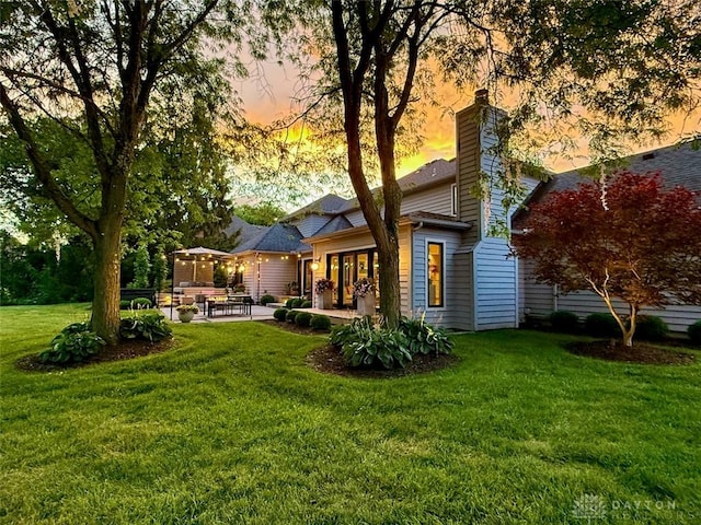 525 Heatherwoode Cir, Springboro, OH 45066 - back of property at dusk featuring a patio, a lawn, and a chimney