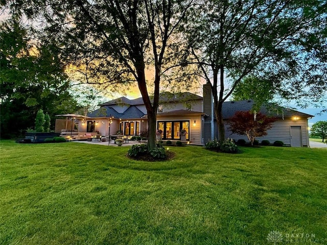 525 Heatherwoode Cir, Springboro, OH 45066 - back of house at dusk featuring a yard, a chimney, and a patio