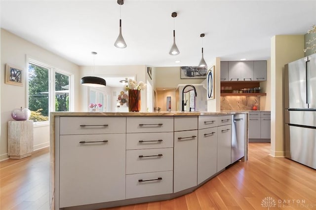 525 Heatherwoode Cir, Springboro, OH 45066 - kitchen with stainless steel appliances, light wood-style flooring, open shelves, pendant lighting, and light countertops