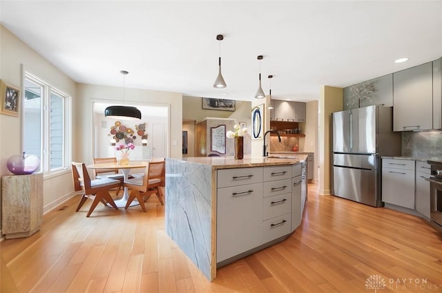525 Heatherwoode Cir, Springboro, OH 45066 - kitchen with freestanding refrigerator, gray cabinetry, light wood finished floors, a center island with sink, and recessed lighting
