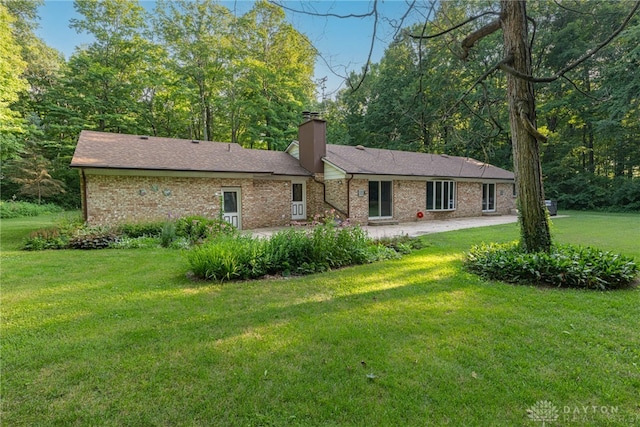 3072 Fowler Rd, Springfield, OH 45502 - rear view of house with a patio area, a lawn, a chimney, and brick siding