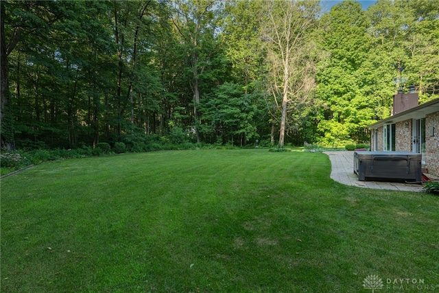 3072 Fowler Rd, Springfield, OH 45502 - view of green lawn with a hot tub, a forest view, and a patio area