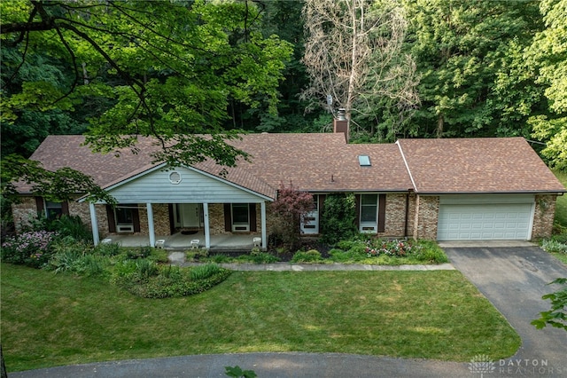 3072 Fowler Rd, Springfield, OH 45502 - ranch-style house with brick siding, asphalt driveway, a front lawn, a porch, and a garage