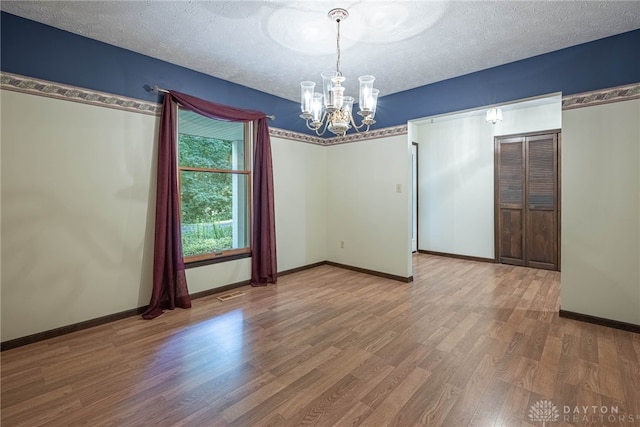 3072 Fowler Rd, Springfield, OH 45502 - empty room with a chandelier, wood finished floors, and a textured ceiling