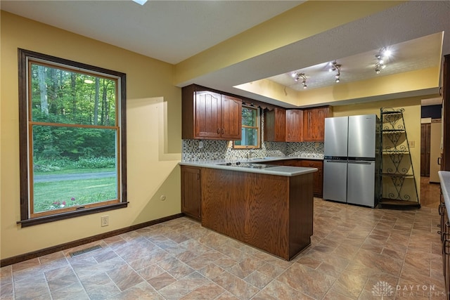 3072 Fowler Rd, Springfield, OH 45502 - kitchen featuring freestanding refrigerator, a peninsula, backsplash, and light stone finish flooring
