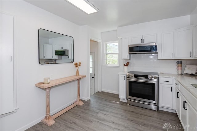 4651 Christopher Ave, Dayton, OH 45406 - kitchen featuring stainless steel appliances, white cabinets, light countertops, light wood-style floors, and backsplash
