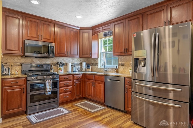 274 Tamarack Trl, Springboro, OH 45066 - kitchen with appliances with stainless steel finishes, a textured ceiling, light wood finished floors, light stone countertops, and brown cabinetry