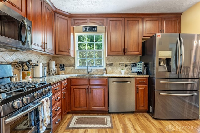 274 Tamarack Trl, Springboro, OH 45066 - kitchen featuring appliances with stainless steel finishes, light wood finished floors, light stone countertops, a textured ceiling, and backsplash