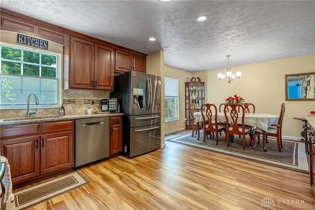 274 Tamarack Trl, Springboro, OH 45066 - kitchen featuring appliances with stainless steel finishes, a textured ceiling, a chandelier, light wood-type flooring, and decorative backsplash