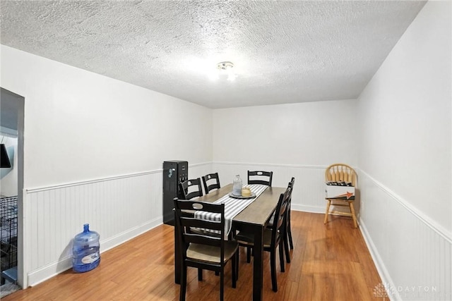 407 Overla Blvd, Englewood, OH 45322 - dining room featuring wood finished floors, a wainscoted wall, and a textured ceiling