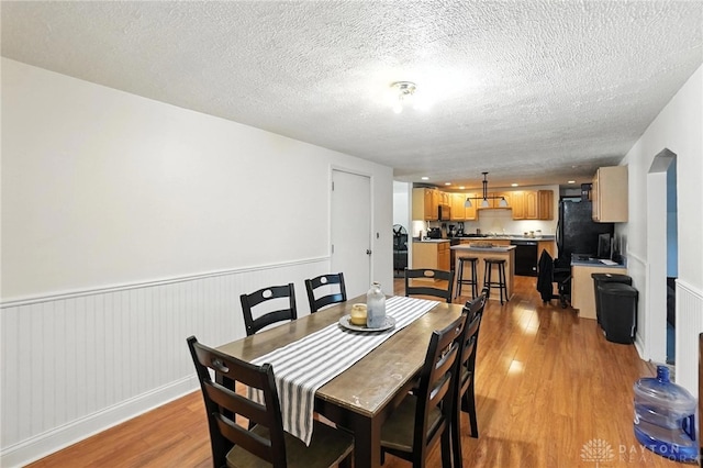 407 Overla Blvd, Englewood, OH 45322 - dining space with light wood-style floors, a wainscoted wall, and a textured ceiling