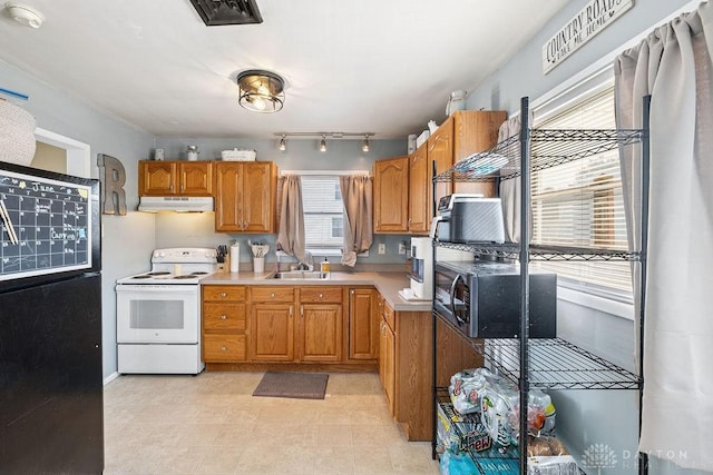 120 N Grant St, Covington, OH 45318 - kitchen with white range with electric stovetop, freestanding refrigerator, under cabinet range hood, light countertops, and brown cabinetry