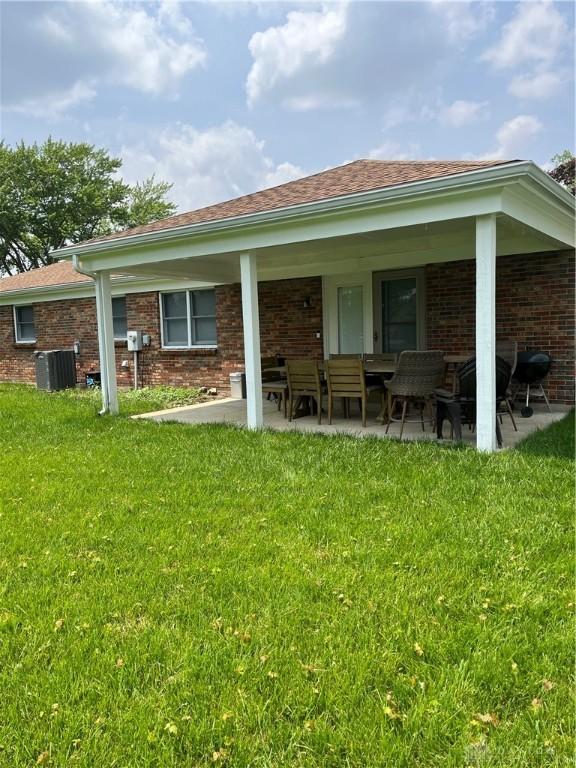 4220 Pleasanton Rd, Englewood, OH 45322 - rear view of property featuring brick siding, a lawn, and a patio