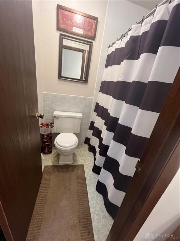 4220 Pleasanton Rd, Englewood, OH 45322 - full bathroom with tile walls, wainscoting, and a shower with curtain