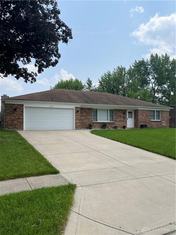 4220 Pleasanton Rd, Englewood, OH 45322 - single story home with concrete driveway, an attached garage, a front lawn, and brick siding