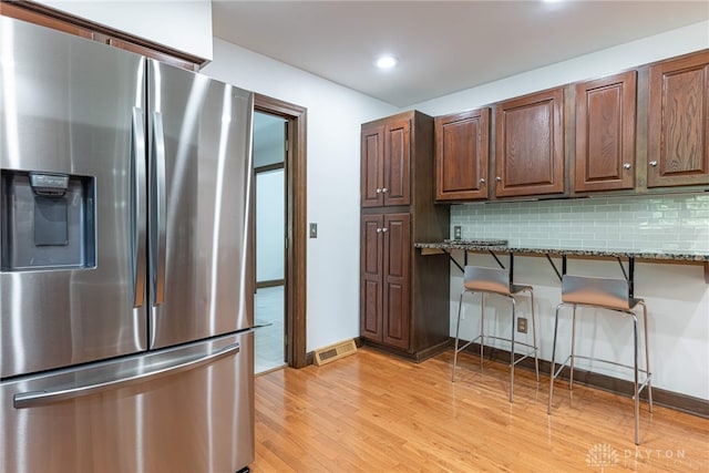 1908 Court Donegal, Middletown, OH 45042 - kitchen featuring stainless steel refrigerator with ice dispenser, a kitchen bar, light wood finished floors, stone countertops, and decorative backsplash