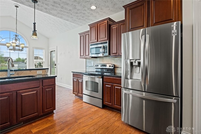 2073 Lincolnshire Dr, Beavercreek, OH 45434 - kitchen featuring stainless steel appliances, lofted ceiling, wood finished floors, decorative backsplash, and a chandelier