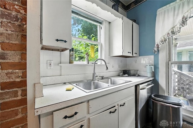 116 Elm St, Franklin, OH 45005 - kitchen with stainless steel dishwasher, white cabinetry, light countertops, decorative backsplash, and brick wall