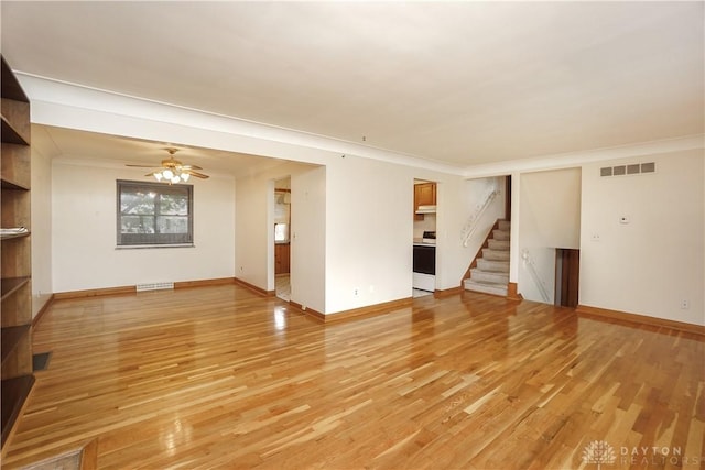 702 W Sharon Rd, Forest Park, OH 45240 - unfurnished living room with stairway, light wood-style floors, crown molding, and a ceiling fan