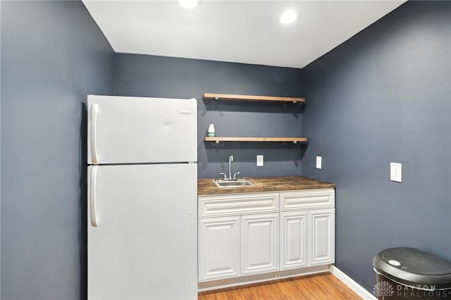 171 Shanda Dr, Monroe, OH 45050 - kitchen with freestanding refrigerator, dark countertops, light wood-style floors, and white cabinetry