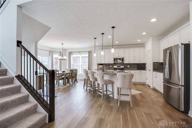 598 Twilight Ln, Dayton, OH 45440 - kitchen featuring appliances with stainless steel finishes, open floor plan, light wood-style floors, decorative backsplash, and recessed lighting