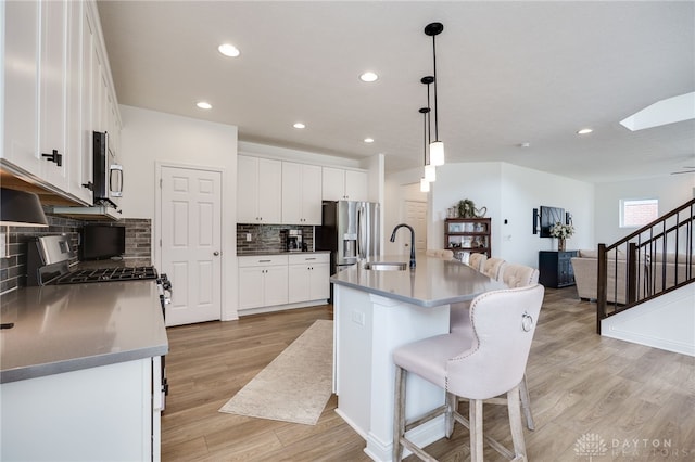 598 Twilight Ln, Dayton, OH 45440 - kitchen featuring stainless steel appliances, light wood-style floors, open floor plan, white cabinets, and decorative backsplash