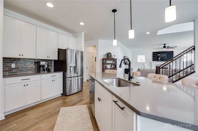 598 Twilight Ln, Dayton, OH 45440 - kitchen featuring appliances with stainless steel finishes, light wood finished floors, backsplash, a ceiling fan, and white cabinetry