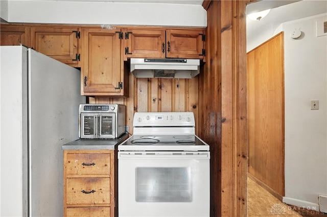 6101 Capri Dr, Cincinnati, OH 45224 - kitchen featuring electric stove, freestanding refrigerator, under cabinet range hood, brown cabinets, and wooden walls