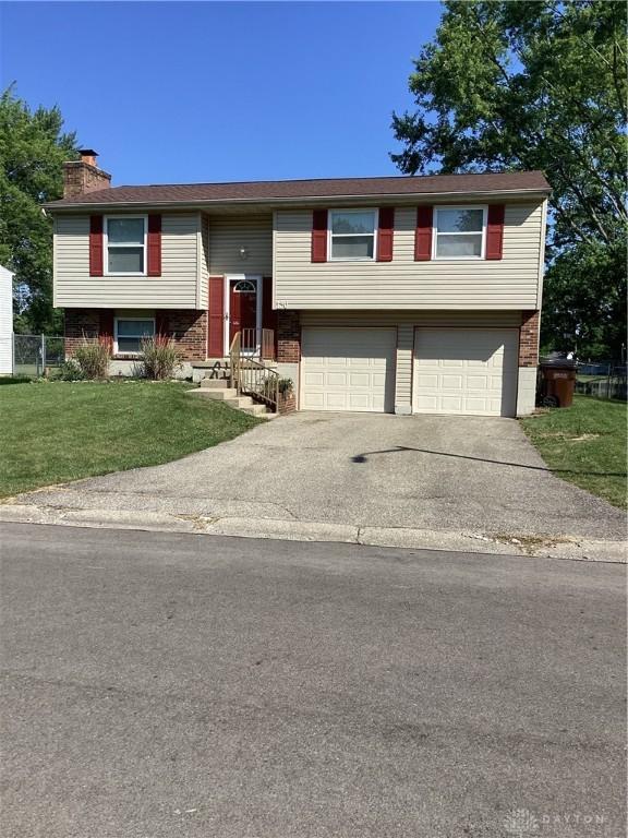 150 Lexington Farm Rd, Englewood, OH 45322 - bi-level home featuring brick siding, a chimney, a garage, driveway, and a front lawn
