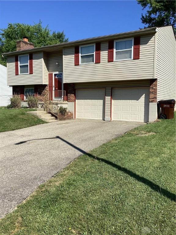 150 Lexington Farm Rd, Englewood, OH 45322 - raised ranch featuring brick siding, an attached garage, driveway, a chimney, and a front yard