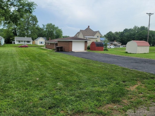 612 E Market St, Xenia, OH 45385 - view of front of house featuring a storage shed, driveway, a front lawn, and brick siding