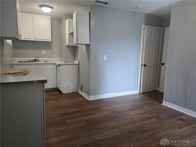 1958 Wesleyan Rd, Dayton, OH 45406 - kitchen featuring white cabinetry, dark wood-style floors, a textured ceiling, and light countertops