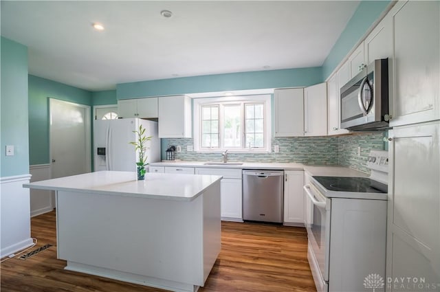 928 E Stroop Rd, Kettering, OH 45429 - kitchen with appliances with stainless steel finishes, dark wood finished floors, tasteful backsplash, a kitchen island, and white cabinetry