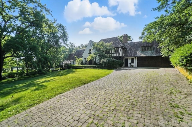 715 E Schantz Ave, Oakwood, OH 45419 - tudor house featuring decorative driveway, a front lawn, a garage, a chimney, and stone siding