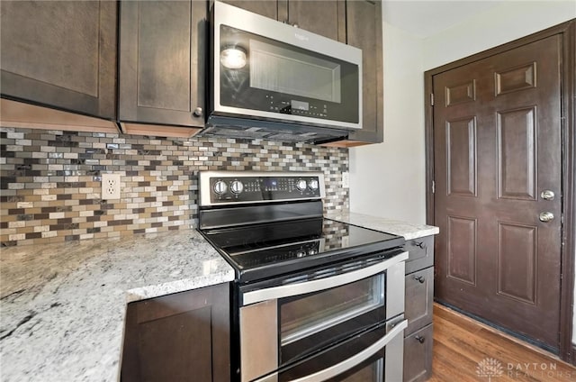 2042 Hilltop Rd, Xenia, OH 45385 - kitchen with appliances with stainless steel finishes, dark brown cabinetry, backsplash, wood finished floors, and light stone countertops