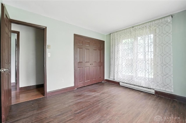 2042 Hilltop Rd, Xenia, OH 45385 - unfurnished bedroom featuring a baseboard heating unit, wood finished floors, and a closet