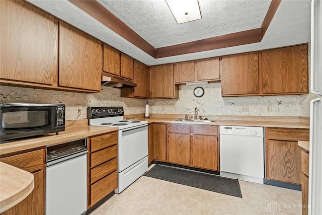 8869 Washington Colony Dr, Dayton, OH 45458 - kitchen featuring white appliances, a textured ceiling, light countertops, brown cabinetry, and under cabinet range hood