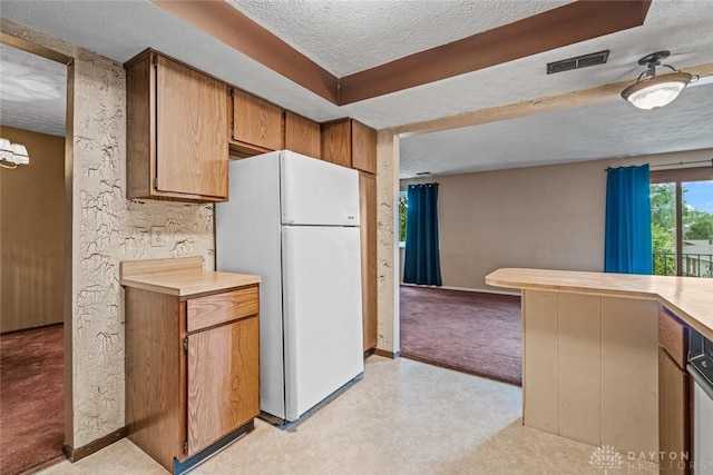 8869 Washington Colony Dr, Dayton, OH 45458 - kitchen with freestanding refrigerator, light colored carpet, a textured ceiling, light countertops, and brown cabinetry