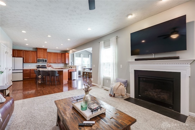 2937 E Ambrosia Ln, Xenia, OH 45385 - living room featuring recessed lighting, dark carpet, a textured ceiling, a fireplace with flush hearth, and ceiling fan