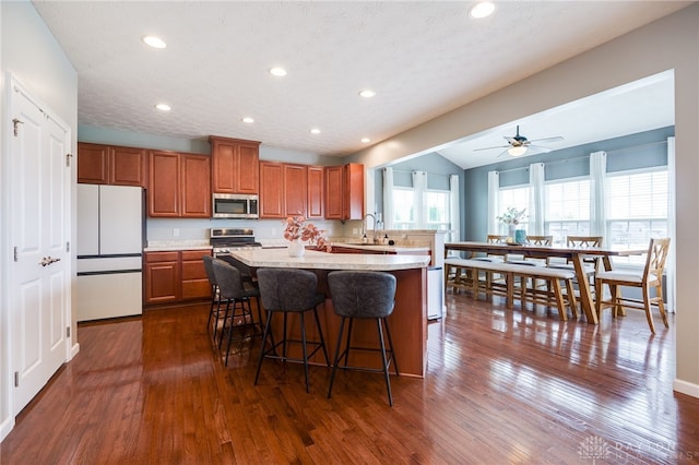 2937 E Ambrosia Ln, Xenia, OH 45385 - kitchen with appliances with stainless steel finishes, brown cabinetry, light countertops, ceiling fan, and a kitchen bar