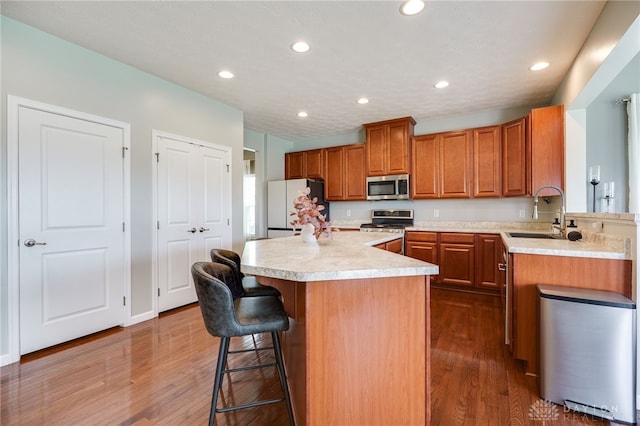 2937 E Ambrosia Ln, Xenia, OH 45385 - kitchen featuring stainless steel appliances, a breakfast bar, brown cabinets, dark wood-style flooring, and a center island