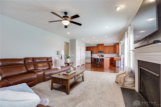 2937 E Ambrosia Ln, Xenia, OH 45385 - living area with ceiling fan, recessed lighting, wood finished floors, a fireplace with flush hearth, and a textured ceiling