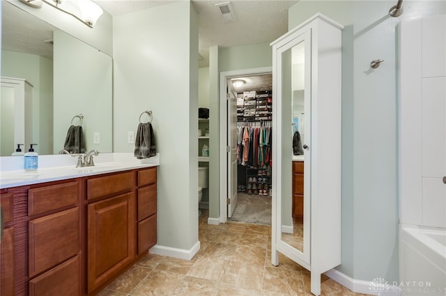 2937 E Ambrosia Ln, Xenia, OH 45385 - bathroom with vanity, a walk in closet, a bathtub, and a textured ceiling