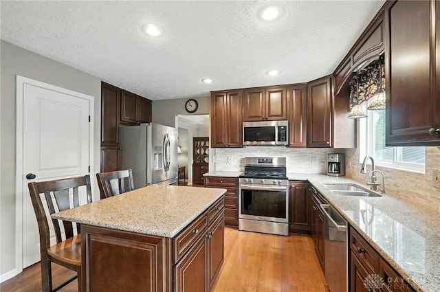 7793 Birchwood Ct, Mason, OH 45040 - kitchen with stainless steel appliances, light wood finished floors, backsplash, light stone counters, and a kitchen island