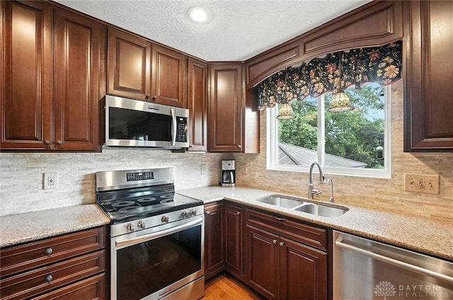 7793 Birchwood Ct, Mason, OH 45040 - kitchen featuring appliances with stainless steel finishes, backsplash, light stone counters, light wood-style flooring, and a textured ceiling