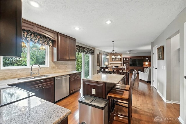 7793 Birchwood Ct, Mason, OH 45040 - kitchen with dishwasher, a kitchen island, a kitchen breakfast bar, tasteful backsplash, and recessed lighting